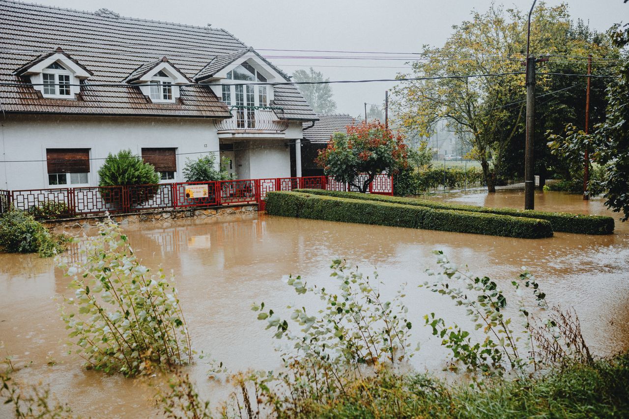 A suburban house surrounded by floodwaters after heavy rain, showing impact of natural disaster.