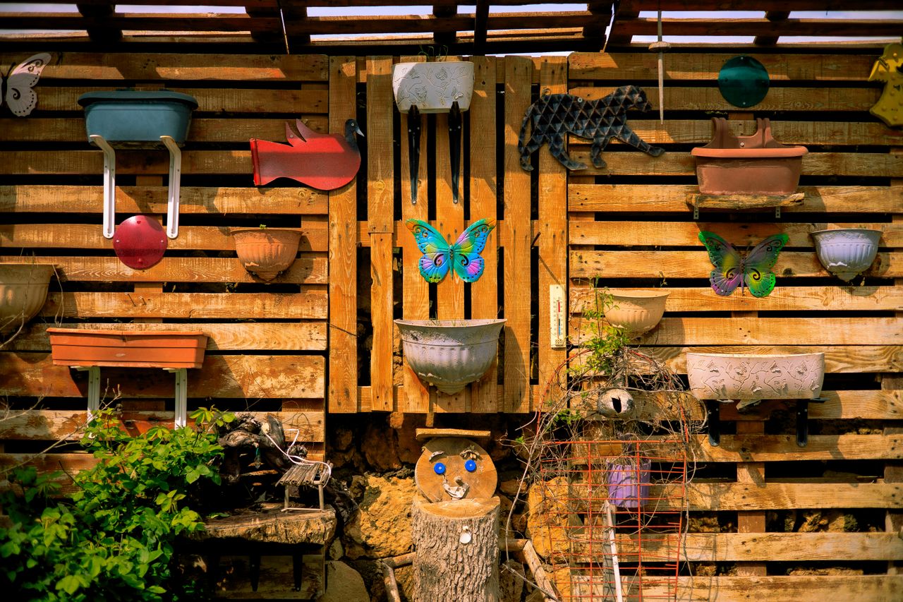 Vibrant wall art and planters brightening a wooden garden in Midyat, Türkiye.